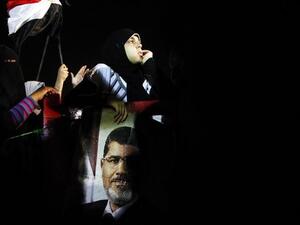 An Egyptian supporter of the Muslim Brotherhood holds the portraits of deposed president Mohamed Morsi during a rally outside Cairo's Rabaa al-Adawiya mosque late on July 7, 2013. [AFP]