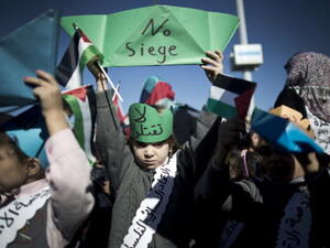 A Palestinian child raises up a paper ship reading 'No siege' during a rally to protest against the Israeli siege of the Gaza Strip on November 30, 2013 at Gaza City harbour. [Mahmud Hams/AFP]