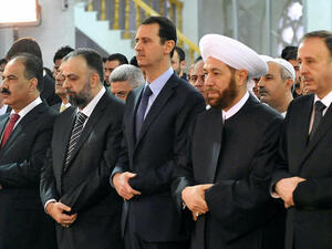 A handout picture released by the official Syrian Arab News Agency (SANA) on October 15, 2013 shows President Bashar al-Assad (C) and Syrian Grand Mufti Ahmed Hassun (C-R) praying at the Sayeda Hassiba mosque in the capital Damascus. (Image credit: AFP)