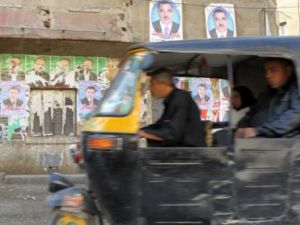 مركبة صغيرة تعبر امام حائظ في القاهرة علقت عليه ملصقات لمرشحين للانتخابات التشريعية المصرية 