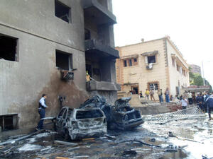 People look at burnt vehicles after a car bomb attack outside a military intelligence building. (Image credit: AFP)