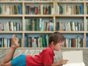 A child reads a book in a library. (Milan Bruchter / Shutterstock.com)