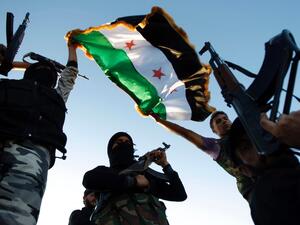 Free Syrian Army members raise their weapons and a revolutionary flag during a training session on the outskirts of Idlib, Syria. (AFP/File)
