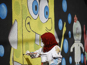 A Palestinian artist paints murals on the walls of a school run by the United Nations Relief and Works Agency for Palestine refugees (UNRWA) in Gaza City. (AFP/File)
