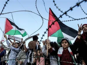 A girl raises a Palestinian flag as another Palestinian boy holds a wooden key symbolizing the return before the barbed-wire east of Gaza City on May 13, 2018. (AFP/ File Photo)