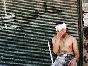 A wounded man sits outside of a shop in Aleppo.  (AFP/File)