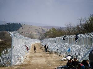 Refugees walk alongside a barbed-wire fence on the Greek-Macedonian border near Gevgelija, on March 1, 2016. (AFP/Dimitar Dilkoff)