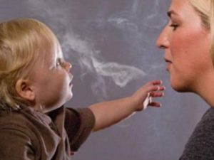 صورة تعبيرية لأم تنفث الدخان في وجه طفلها وتعرضه للخطر 