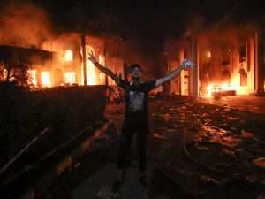 An Iraqi demonstrator poses outside the torched Iranian consulate on Friday, as protests over poor public services broke out in the city of Basra. (AFP)