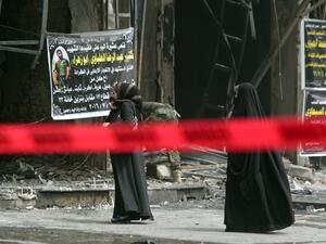 Iraqi women walk past the site of Sunday's bombing, marked off with red tape. (AFP/Sabah Arar)