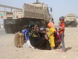 Iraqis displaced from al-Buthiab area north of Ramadi sit on the side of a street after arriving at a makeshift camp on June 25, 2016. (AFP/Moadh al-Dulaimi)