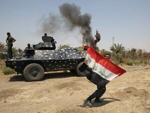 A member of the Iraqi security forces holds an Iraqi national flag in Khalidiya, east of Ramadi, the capital of Anbar province, on August 1, 2016, during ongoing fighting against Daesh. (AFP/Ahmad al-Rubaye)