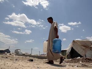 Abu Shiab carries water on May 31, 2016 at the Alexanzan camp in the Dora neighburhood outside of Baghdad where he is taking shelter with his family after they were displaced from the Jbeil, a village near Fallujah due to clashes between pro-government forces and Daesh. (AFP/Sabah Arar)