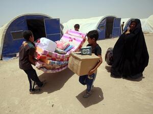 Iraqis displaced from the city of Fallujah collect aid distributed by the Norwegian Refugee Council at a newly opened camp in Amriyat al-Fallujah on June 27, 2016, south of Fallujah. (AFP/Ahmad al-Rubaye)