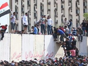 Iraqi protesters climb over a concrete wall surrounding the parliament on April 30.(AFP Photo)