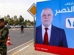 A member of Kurdish security forces stands near a campaign poster for Iraqi Prime Minister Haider al-Abadi for the May 12 parliamentary elections. (AFP/ File Photo)