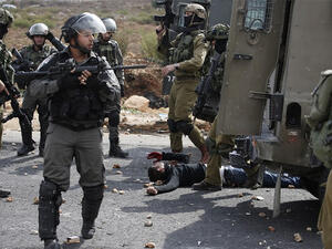 Israeli soldiers stand over an injured Palestinian man during clashes near Ramallah in the West Bank, October 7, 2015. (AFP/File)