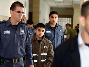 Ahmed Manasra, a 13-year old Palestinian accused of taking part in the stabbing of two Israelis earlier this month, is escorted by Israeli security during a hearing at a Jerusalem court on October 30, 2015. (AFP/Ahmad Gharabli)