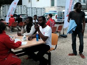 Migrants speak with members of the Italian Red Cross who help them to contact their family on March 6, 2017. (AFP/Alberto Pizzoli)