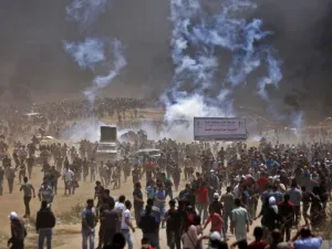 Palestinians run for cover from tear gas during clashes with Israeli security forces near the border between Israel and the Gaza Strip, east of Jabalia/AFP