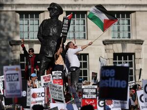 Pro-Palestine demonstrators hold placards and wave flags during a protest opposite the entrance to Downing Street in central London /AFP