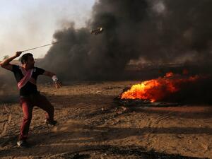 A Palestinian demonstrator uses a slingshot during clashes with Israeli forces along the border with the Gaza strip (AFP/File Photo)