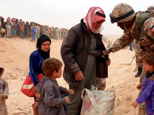 A Jordanian soldier scans newly arrived Syrian refugees as they wait to cross the border. (AFP/ File Photo)