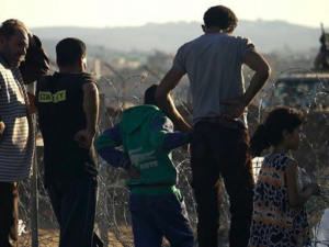 A Jordanian army soldier stands on a jeep behind barbed wire as displaced Syrians from Daraa fleeing shelling by pro-government forces  in a makeshift camp, near the town of Nasib, southern Syria, July 2, 2018. (AFP Photo/Mohamad Abazeed)