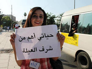 A young Jordanian woman holds a placard that reads, "My life is more important than family honor." (File photo)