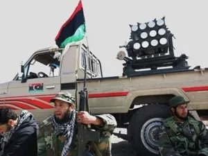 ثوار ليبيون يجلسون عند سيارة محملة بقاذفة صواريخ قرب اجدابيا