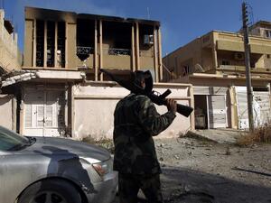 A fighter loyal to Libya's internationally recognized government walks along damaged a street in Benghazi after seizing the center of the city on Feb. 23, 2016 from Daesh militants. (AFP/Abdullah Doma)