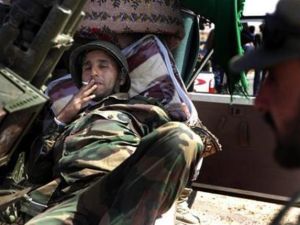 مقاتل معارض للزعيم الليبي معمر القذافي يدخن على خط الجبهة بين بن جواد وراس لانوف
