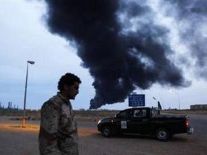 احد انصار القذافي يمر امام نقطة تفتيش قرب طرابلس وتبدو سحابة من الدخان تتصاعد من دبابة تعرضت للقصف