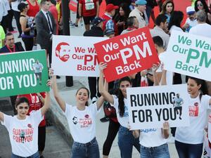Supporters of Lebanon's resigned prime minister Saad Hariri hold up placards demanding his return from Saudi Arabia on the starting line of Beirut's annual marathon on November 12, 2017 (Anwar Amro/AFP)