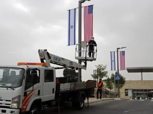 A worker installs decorations of Israeli and US flags in front of the US Consulate in Jerusalem where US officials will install the new US Embassy/ AFP