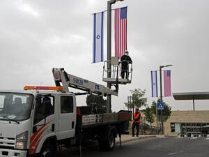 A worker installs decorations of Israeli and US flags in front of the US Consulate in Jerusalem where US officials will install the new US Embassy/ AFP
