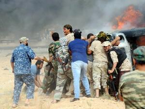 Forces loyal to Libya's UN-backed unity government attempt to evacuate a passenger stuck inside a vehicle following a car-bomb attack carried out by Daesh near Sirte on June 2, 2016. (AFP/Mahmud Turkia)