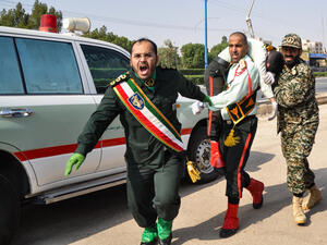 This picture taken on September 22, 2018 in the southwestern Iranian city of Ahvaz shows an Iranian soldier carrying an ijured comrade at the scene of an attack on a military parade that was marking the anniversary of the outbreak of its devastating 1980-1988 war with Saddam Hussein's Iraq (AFP)