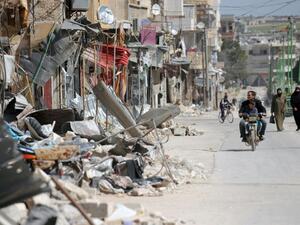 Civilians drive past damaged buildings in Maarat al-Numan, Syria. (AFP/File)