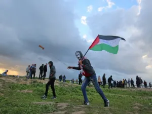 A Palestinian protester wearing a Guy Fawkes mask while holding a Palestinian flag and hurling a slingshot following a demonstration at Gaza border with Israel. (SAID KHATIB / AFP)