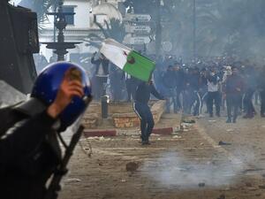 A member of the Algerian security forces holds a rock in his hand as riot forces repsond to protesters gathering in the capital Algiers on March 1, 2019. (AFP)