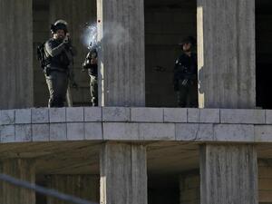 An Israeli soldier fires a tear gas canister at Palestinian stone throwers following a raid in the West Bank city of Ramallah, 10th of December. (AFP)