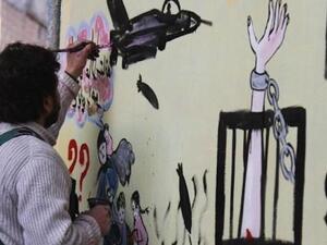 Syrian artist Aziz al-Asmar works on a mural depicting the war ahead of the start of the Astana peace talks. (AFP/ File Photo)