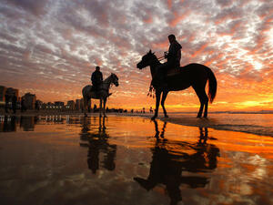 Men riding horses on the beach as the sun sets over Gaza City on January 20, 2017. (AFP PHOTO / MOHAMMED ABED)


