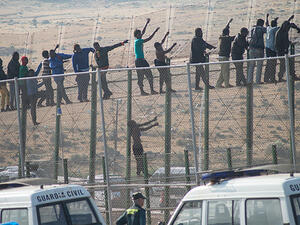 Would-be immigrants stand atop a border fence separating Morocco from the Spanish enclave of Melilla on May 1, 2014, following a morning assault on the border in an attempt to cross into Spain. (AFP/File)
