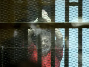 This file photo taken on June 18, 2016 shows Egypt's ousted Islamist president Mohamed Morsi, wearing a red uniform, gesturing from behind the defendant's bars during his trial on espionage charges at a court in Cairo. (AFP FILE)