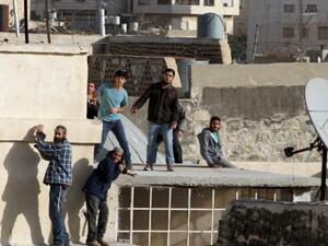 Jewish settlers stand on the roof of a building after entering two homes in the center of Hebron on January 21, 2016. (AFP/Hazem Bader)