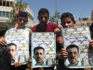Three young demonstrators hold images of Sami Janazreh. (Palsolidarity.org)