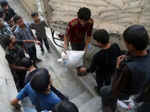 Syrians offload aid after a convoy of Syrian Arab Red Crescent and UN vehicles arrived in a rebel-held area on the outskirts of Damascus. (AFP/Amer Almohibany)