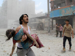 A man carries a young girl who was injured in a reported barrel-bomb attack by government forces on June 3 in Kallaseh district in the northern city of Aleppo, Syria. (AFP/File)